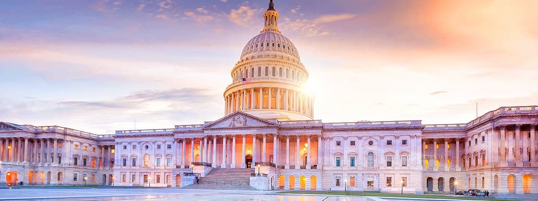 Le Capitole des États-Unis au coucher du soleil, avec son dôme illuminé et sa façade néoclassique.