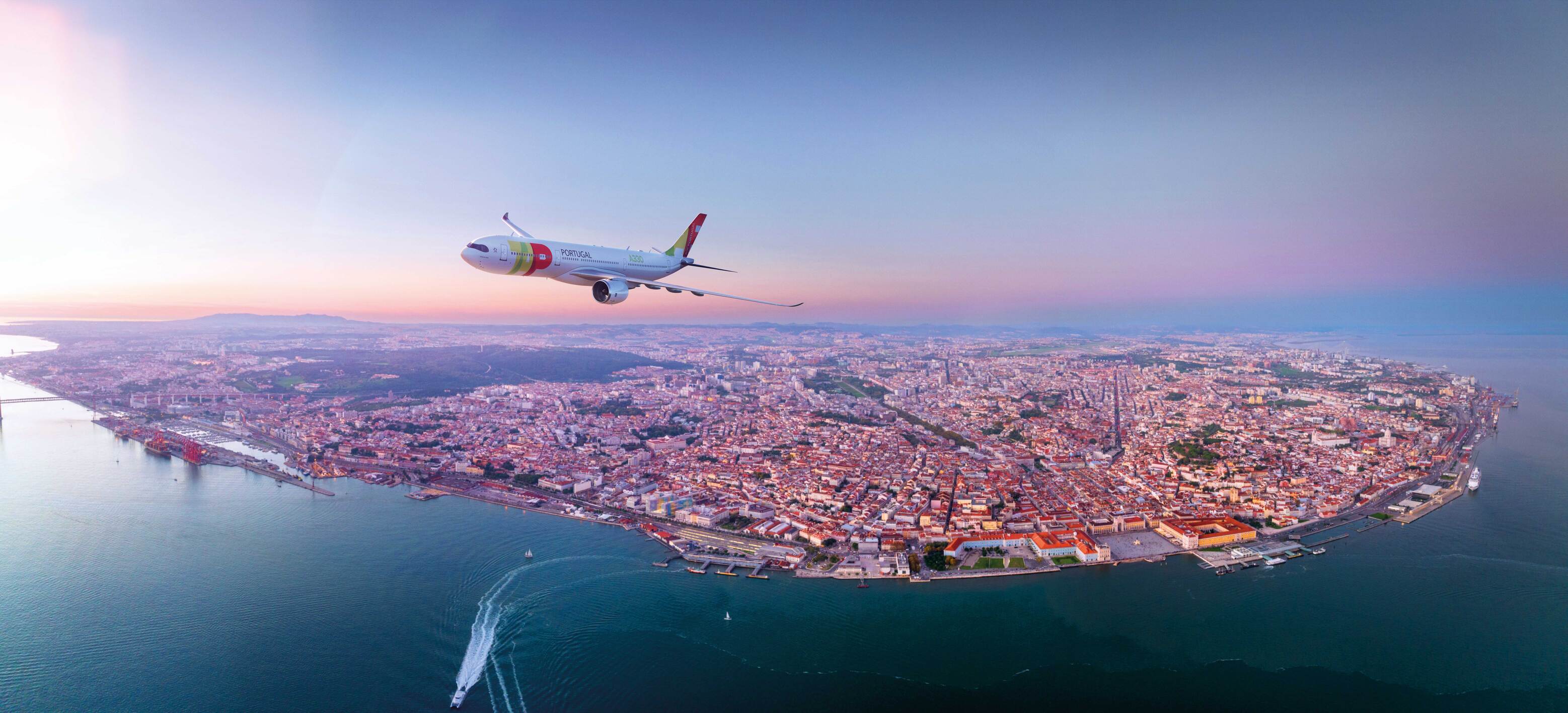 Avión de TAP sobrevolando Lisboa al atardecer, con la ciudad y el río Tajo al fondo.